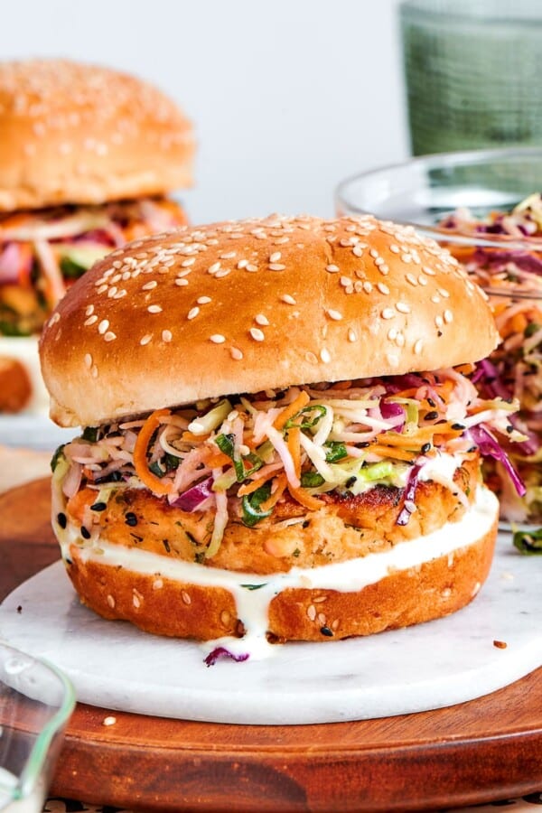 seasoned salmon patty showing fresh herbs and lemon zest inside assembled burger.