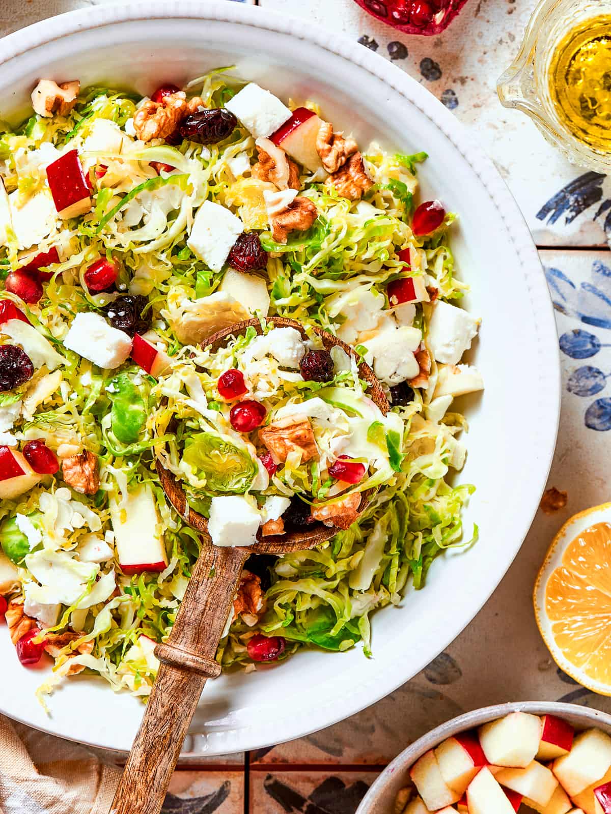 Wooden salad tongs resting in a bowl of Brussels sprouts salad ready to be served.
