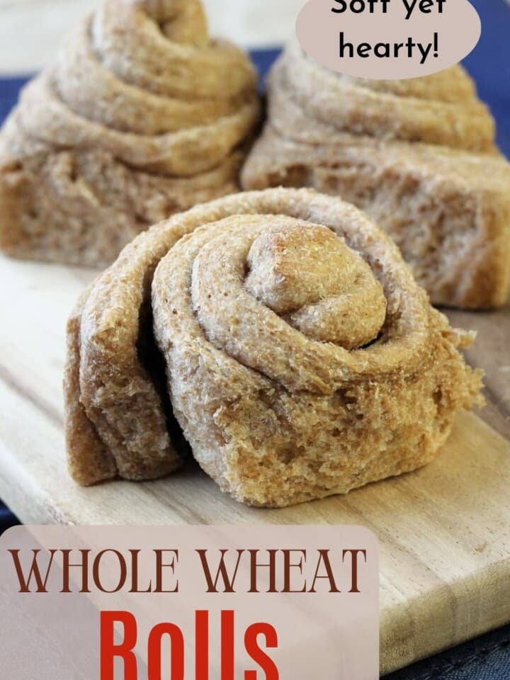 Freshly baked whole wheat rolls with soft centers shown cooling on a cutting board after baking.