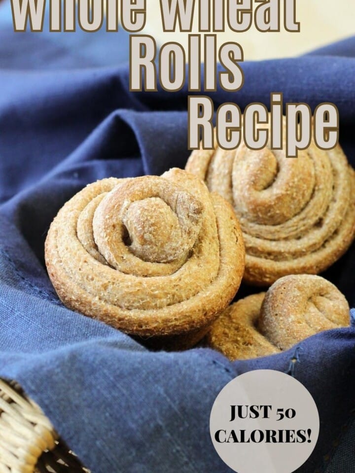 A basket of spiral whole wheat rolls with golden crusts arranged for serving on a kitchen table.