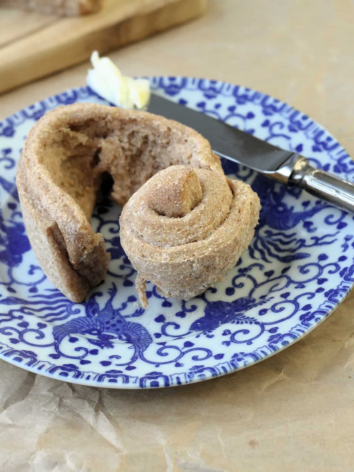 A whole wheat roll ripped open with visible fluffy interior.