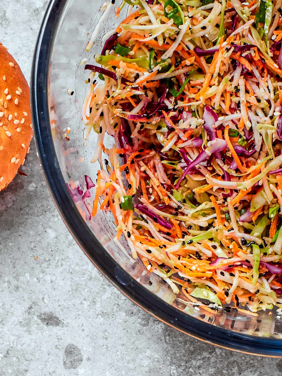 Healthy broccoli slaw served in a clear glass bowl showing off colors and textures of the dish.