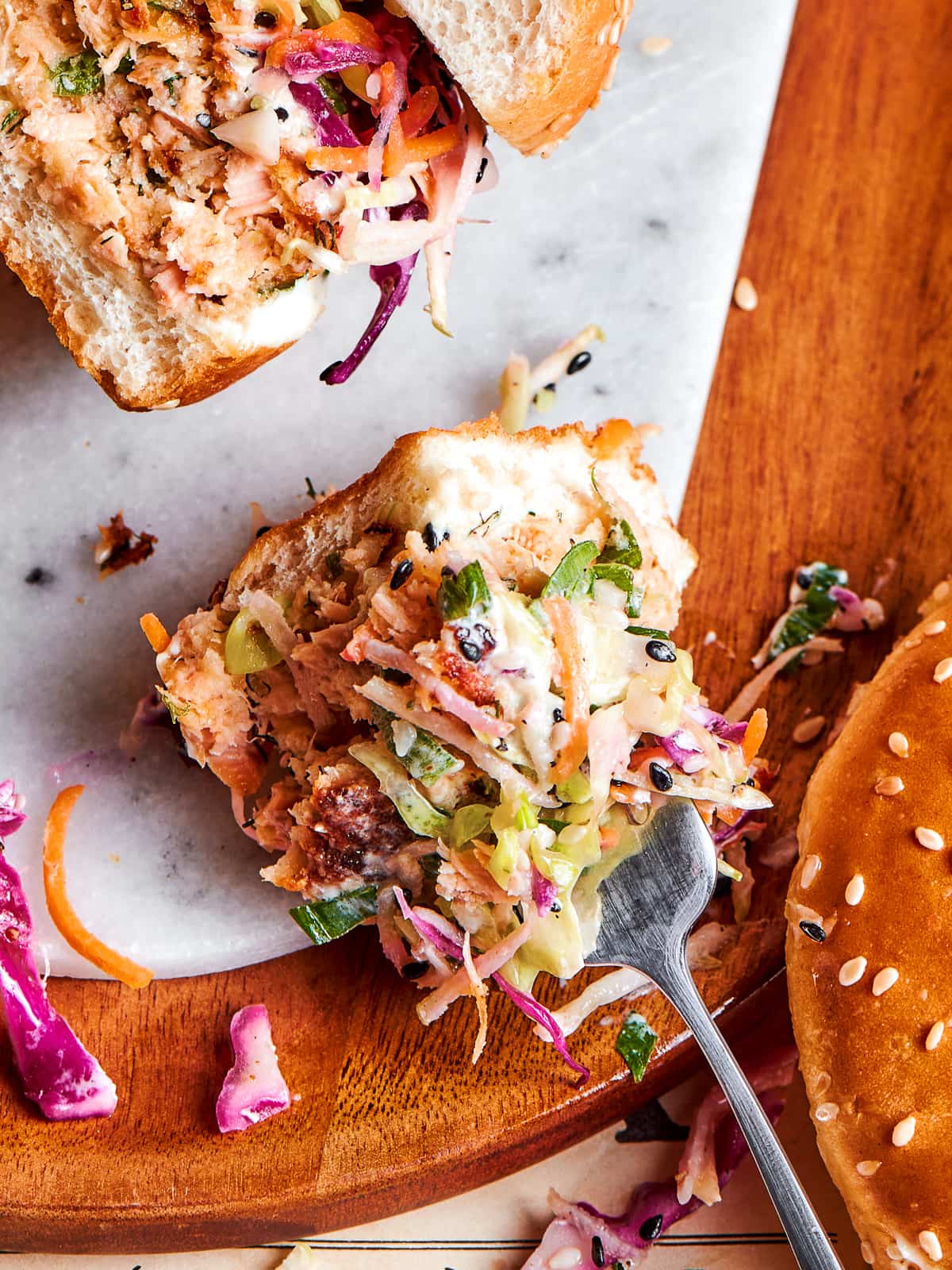 A silver fork scooping up broccoli slaw with visible sesame seeds, carrots, and cabbage.