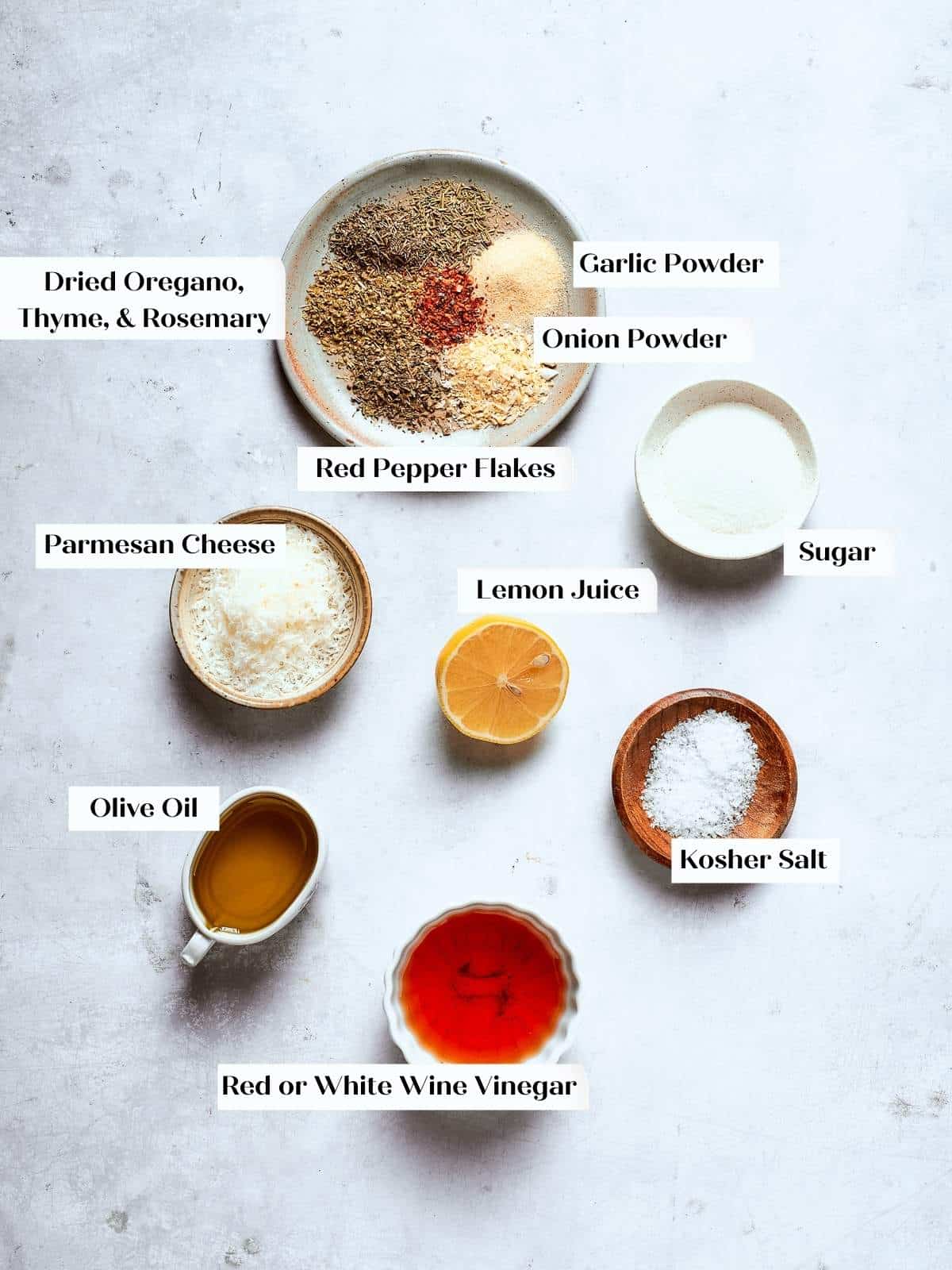 Ingredients for Italian salad dressing arranged on a countertop, including olive oil, vinegar, and spices.
