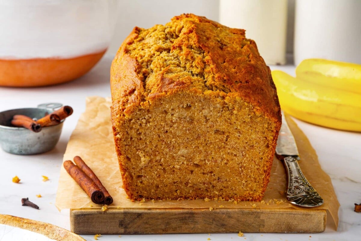 Sliced pumpkin banana bread resting on wooden cutting board, ready for serving.