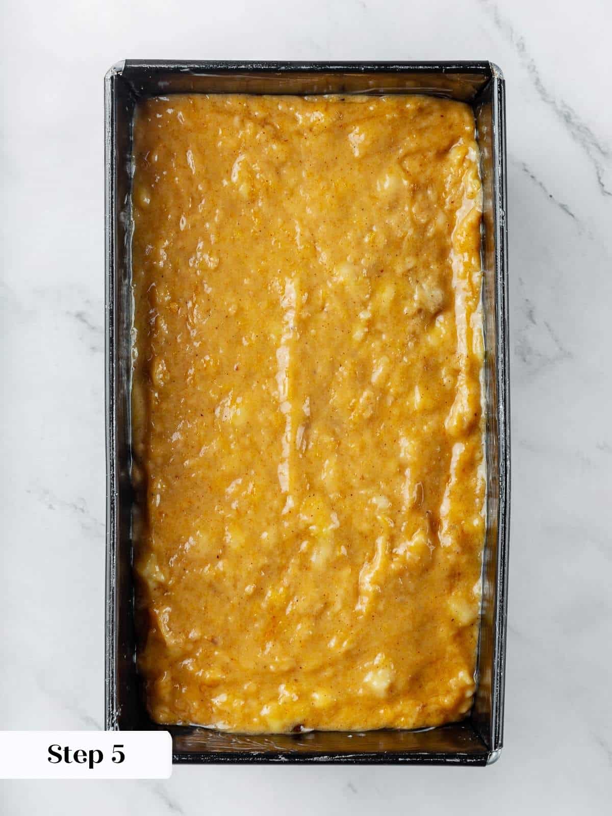 Unbaked pumpkin banana bread batter spread evenly in loaf pan before baking.