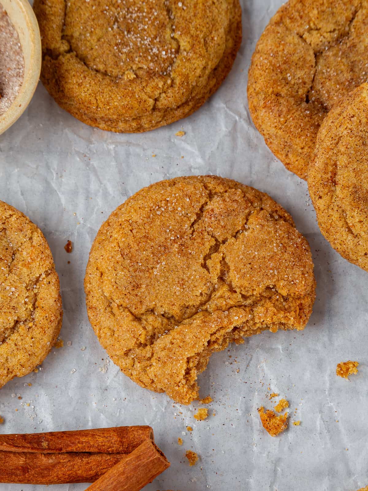 Pumpkin snickerdoodle cookie with small bite missing, showing chewy interior texture.