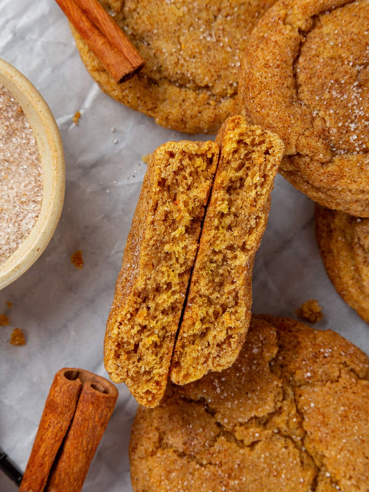 Pumpkin snickerdoodle cookie broken in half to reveal chewy center and sugar coating.