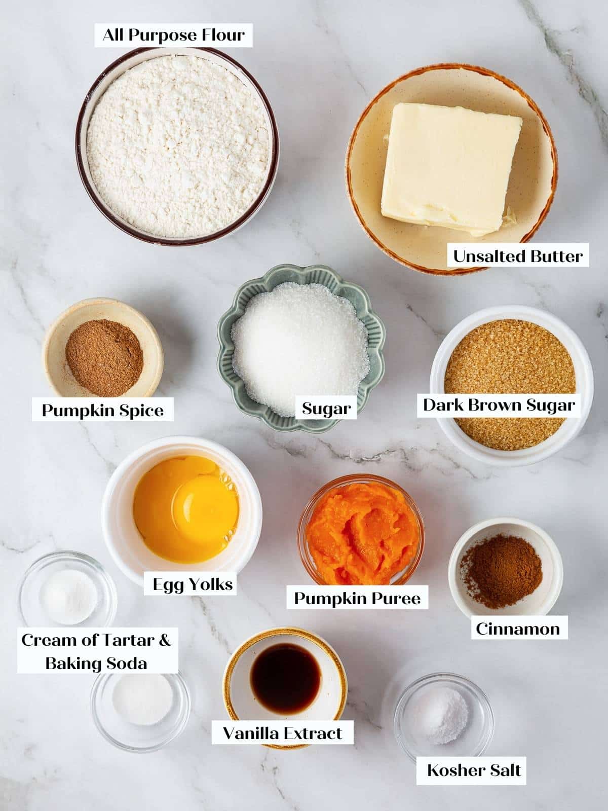 Ingredients for pumpkin snickerdoodle cookies arranged on countertop, including pumpkin puree, spices, and sugar.