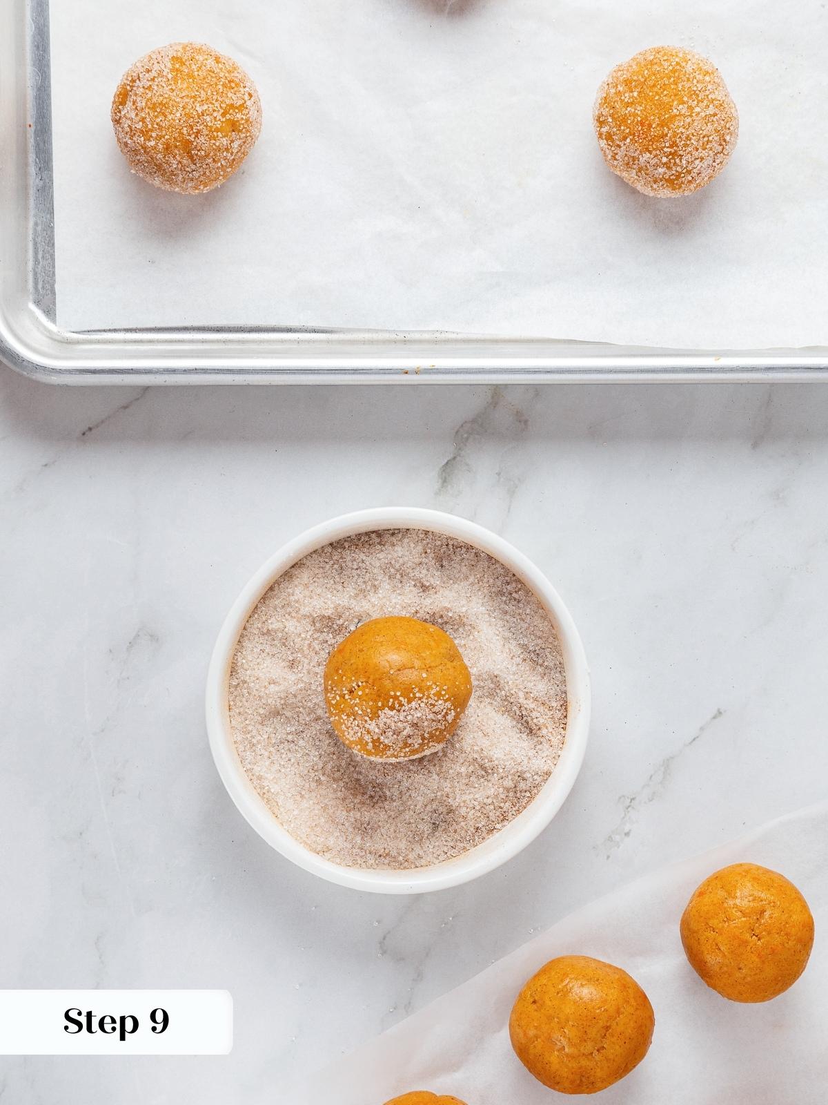 Pumpkin snickerdoodle dough balls being rolled in spiced sugar before baking.