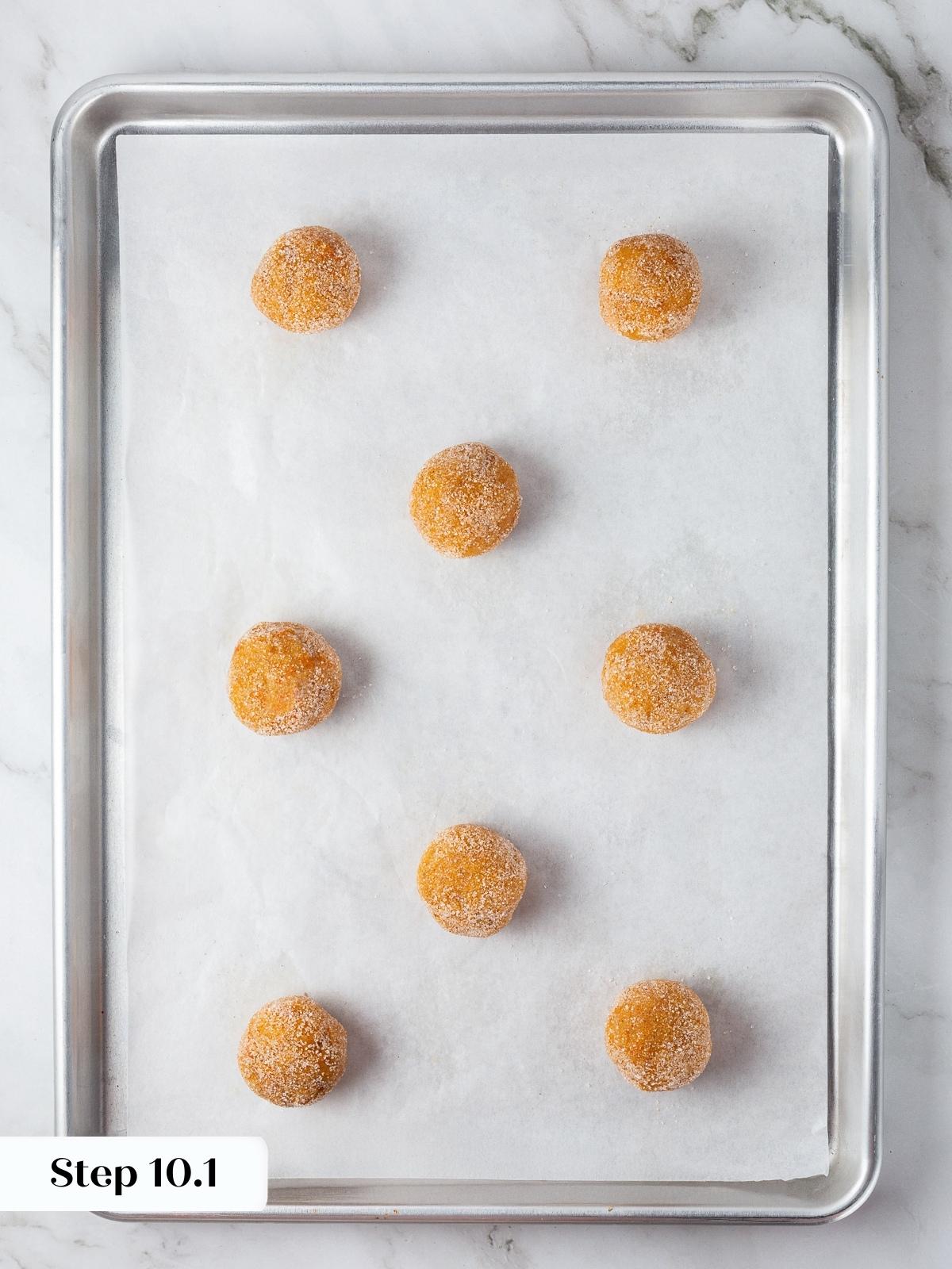 Unbaked pumpkin snickerdoodle dough balls arranged on parchment-lined baking sheet.