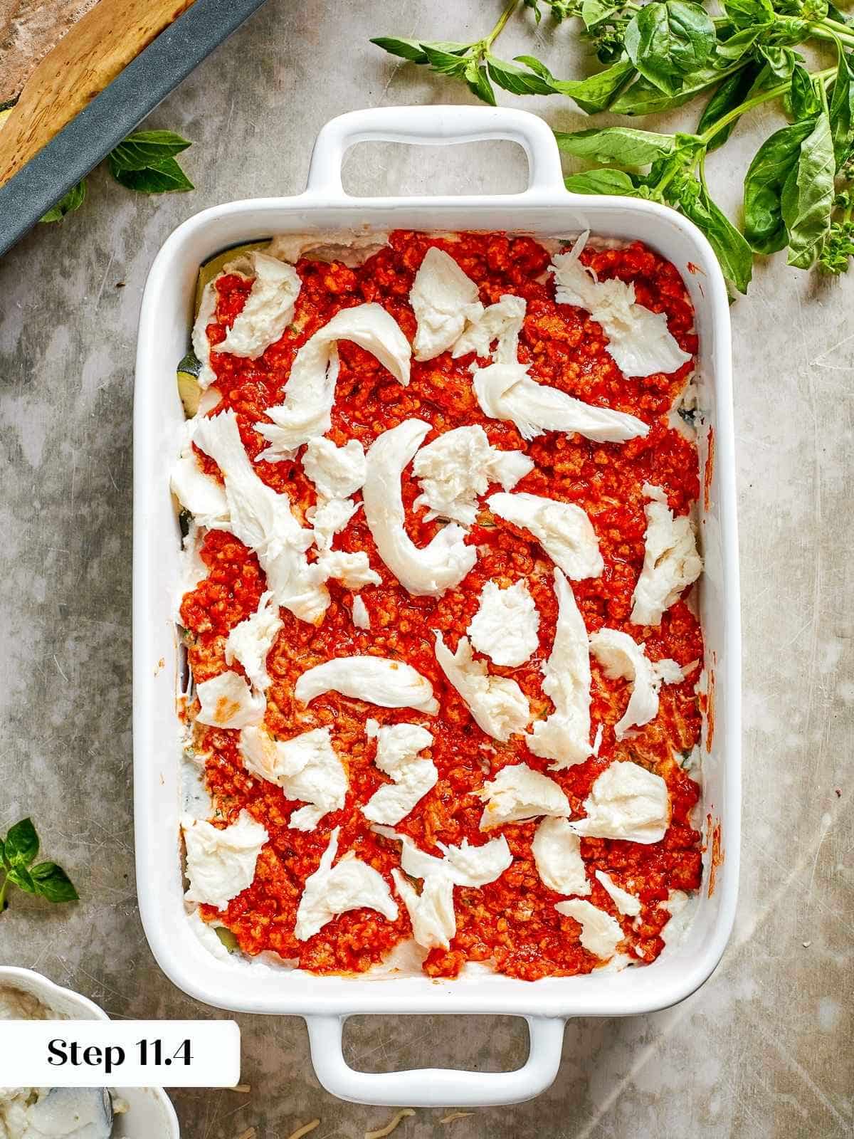 Fresh mozzarella slices being layered into the lasagna before final baking.