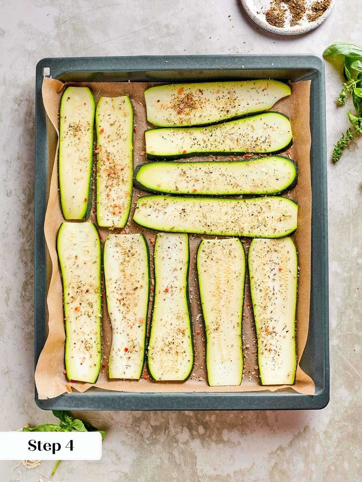 Baking dish filled with seasoned zucchini planks ready for roasting.