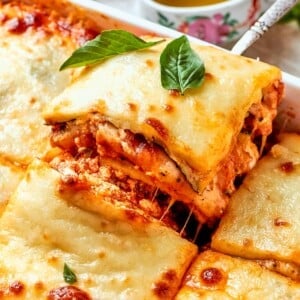 Square of zucchini lasagna lifted from pan with clean lines and melty cheese.
