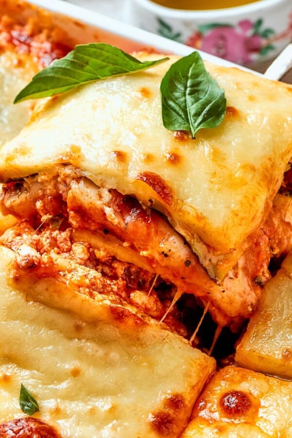 Square of zucchini lasagna lifted from pan with clean lines and melty cheese.