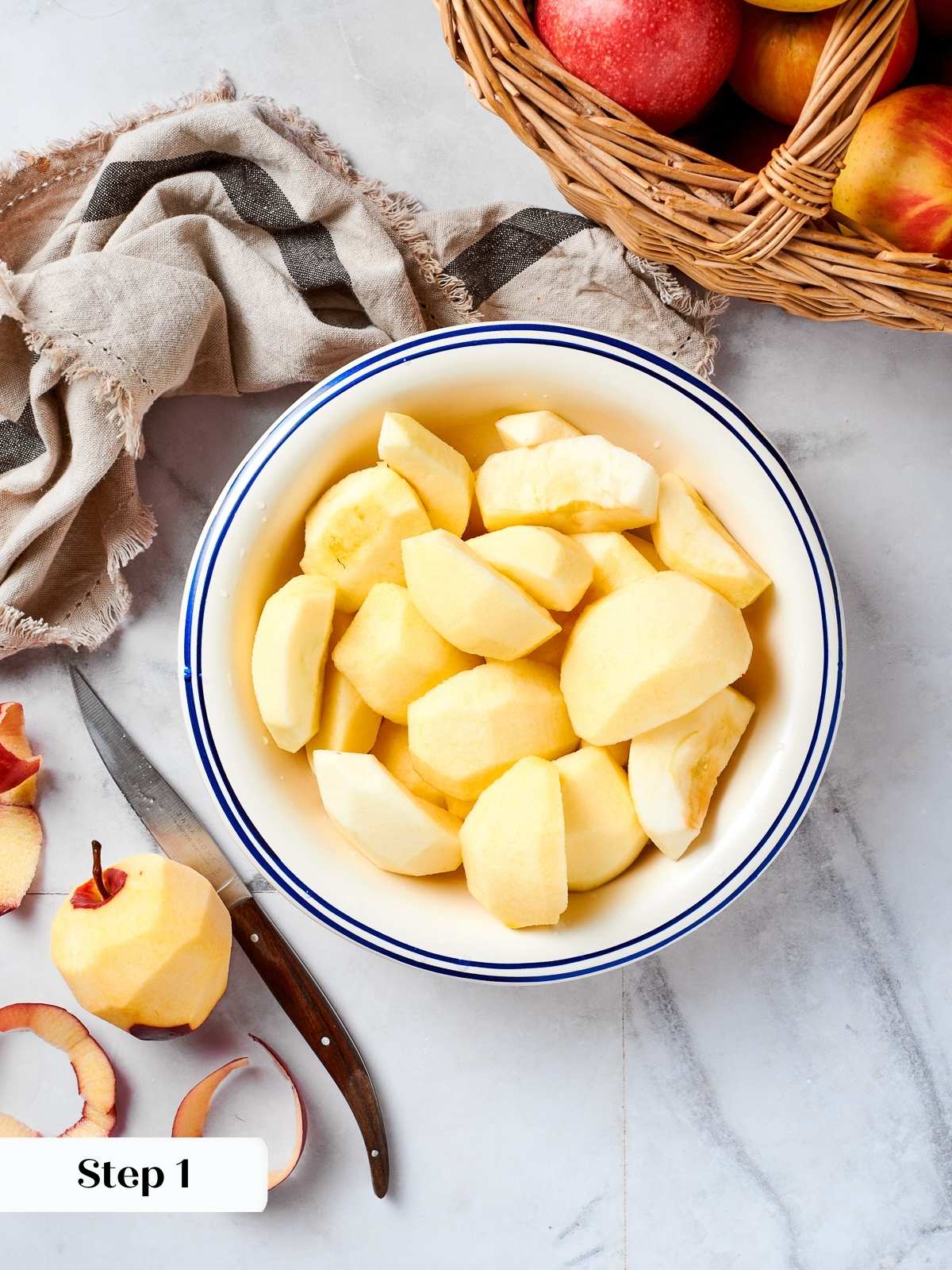 Fresh apples being peeled and quartered on a countertop, preparing ingredients for homemade applesauce.