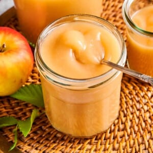 Homemade applesauce in a jar resting on a wicker placemat, surrounded by natural autumn light.