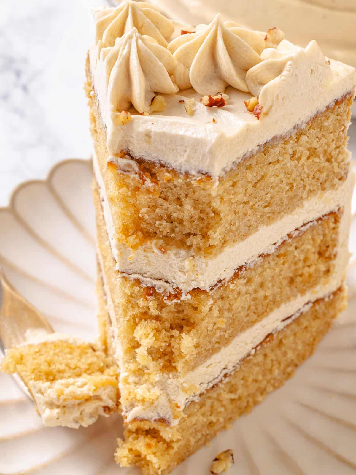 ork holding bite of maple cake showing three layers with frosting between.