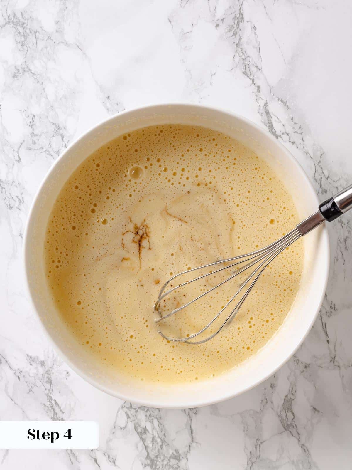 Syrup added carefully into wet ingredients for maple cake batter.