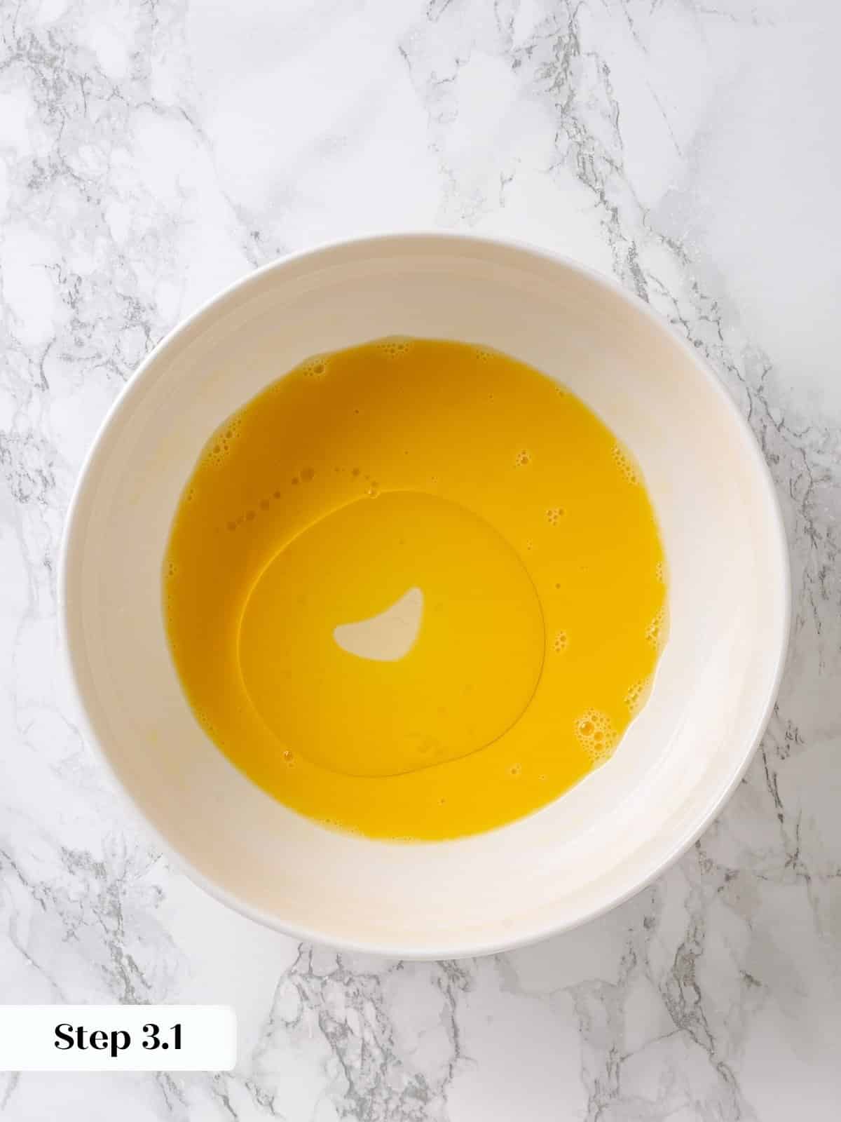 Oil being poured slowly into whisked eggs to create emulsion for batter.
