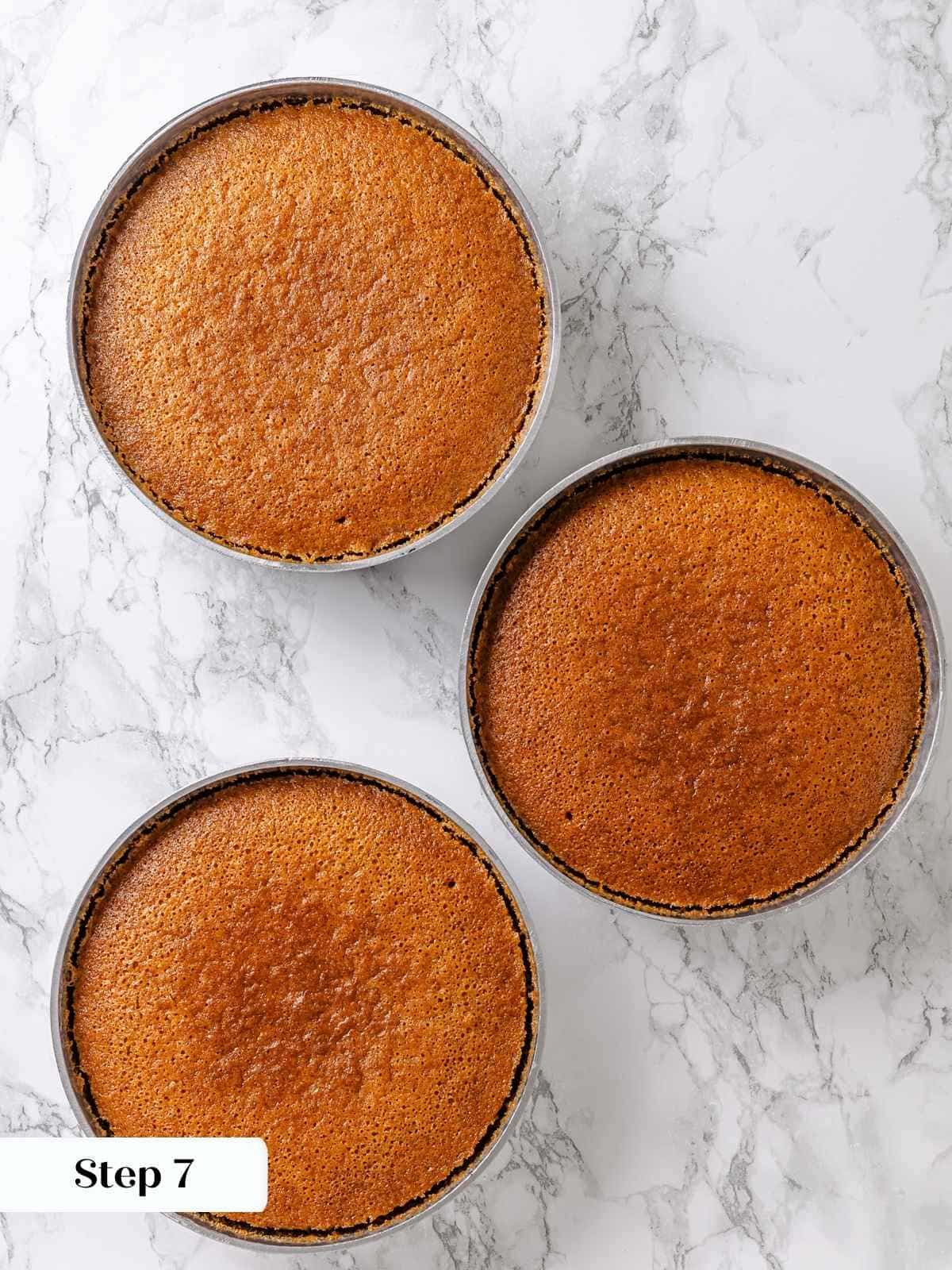Maple cake layers baked golden in round pans, cooling before frosting.