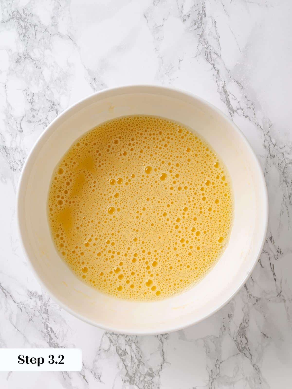 Oil whisked into eggs until smooth, creating emulsion for maple cake batter.