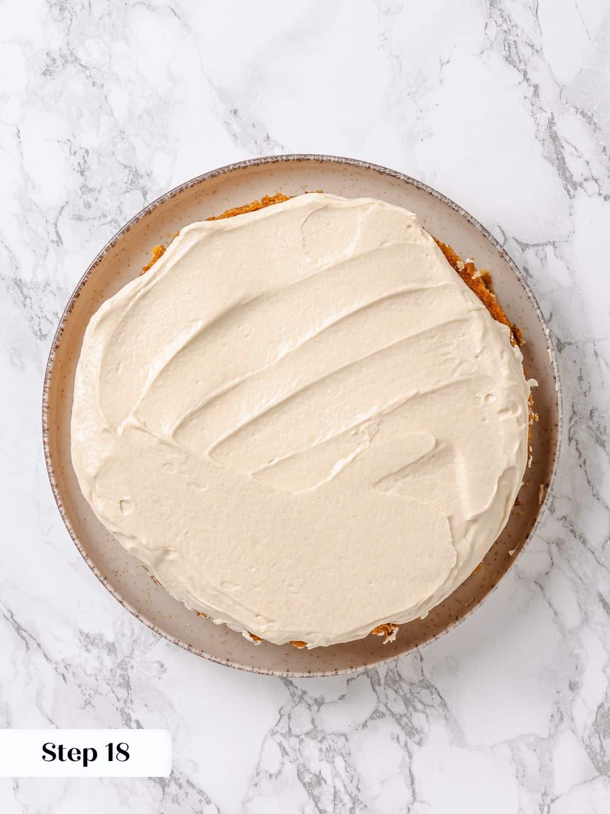 First cake layer covered with thin frosting crumb coat, preparing for final maple frosting.
