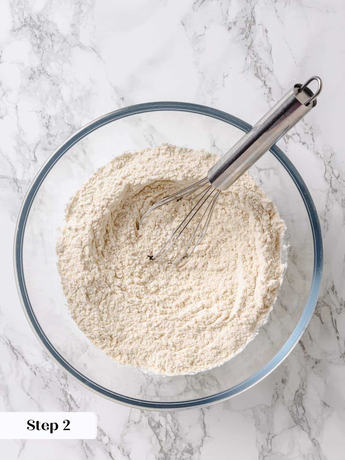 Bowl of flour mixture being whisked together to prepare dry ingredients for maple cake.