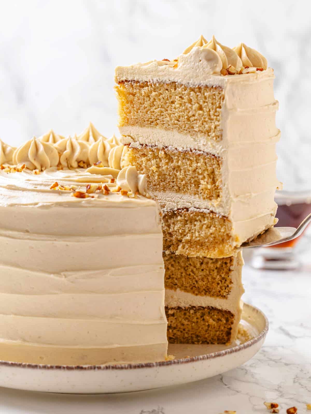 Maple cake slice being served, frosting visible between soft cake layers on serving utensil.