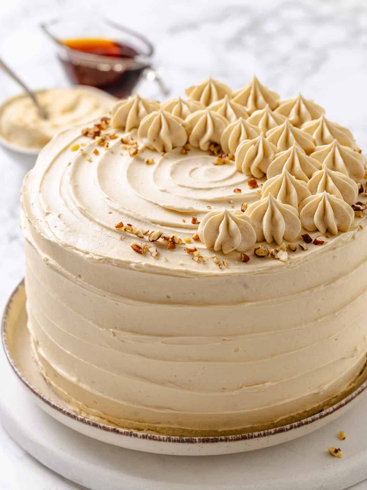 Maple cake slice resting on a white plate, fluffy frosting layered beautifully across tender crumb.