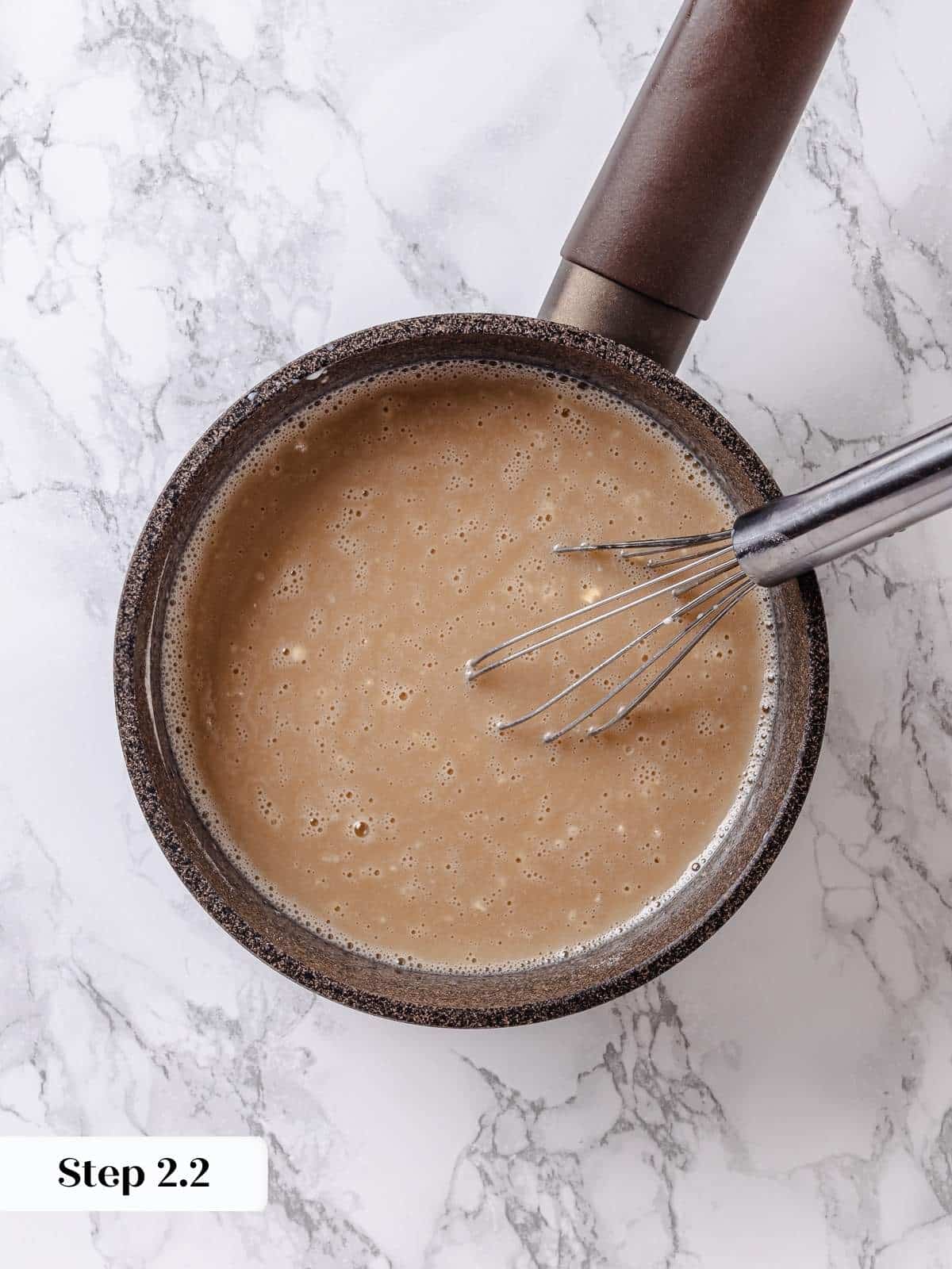 Maple syrup poured into mixture on stove, deepening flavor for creamy frosting base.