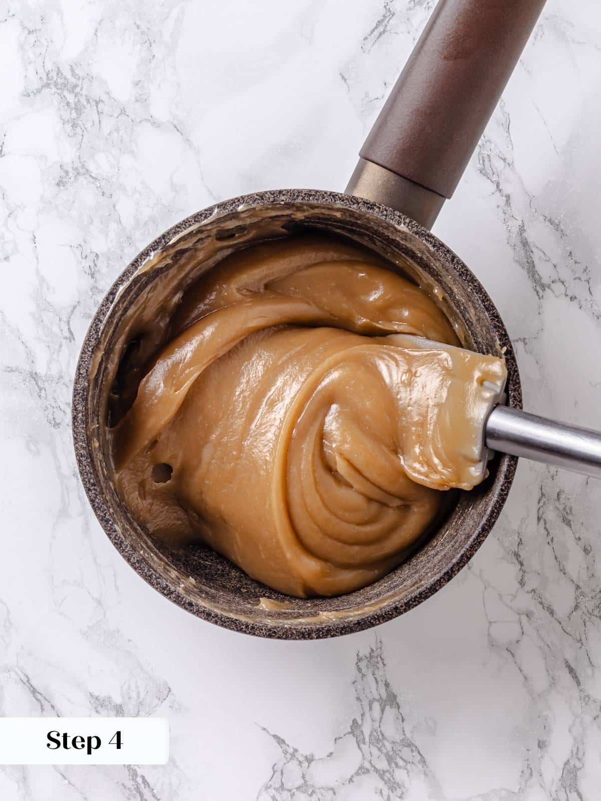 Maple frosting base thickened in pan, forming clumps that hold shape when stirred.