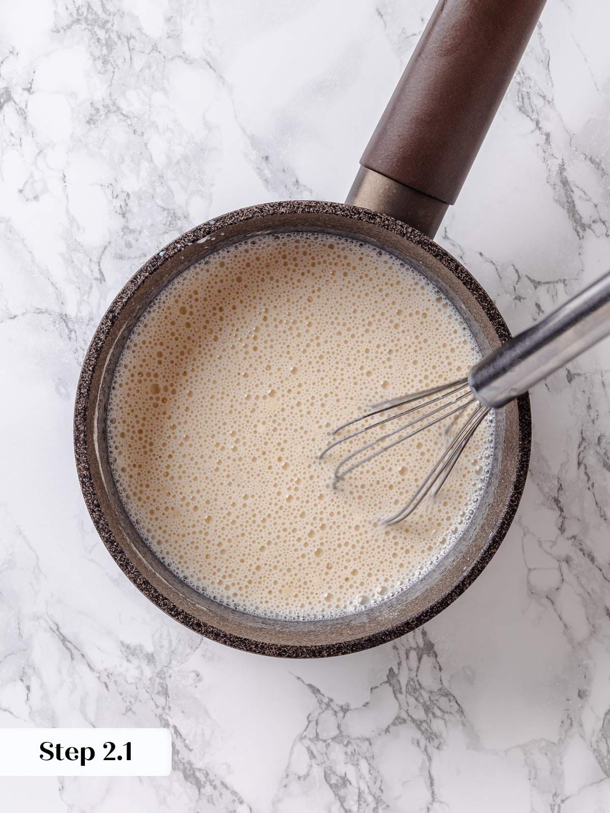 Whisk stirring milk into dry ingredients, starting the base for creamy maple frosting.