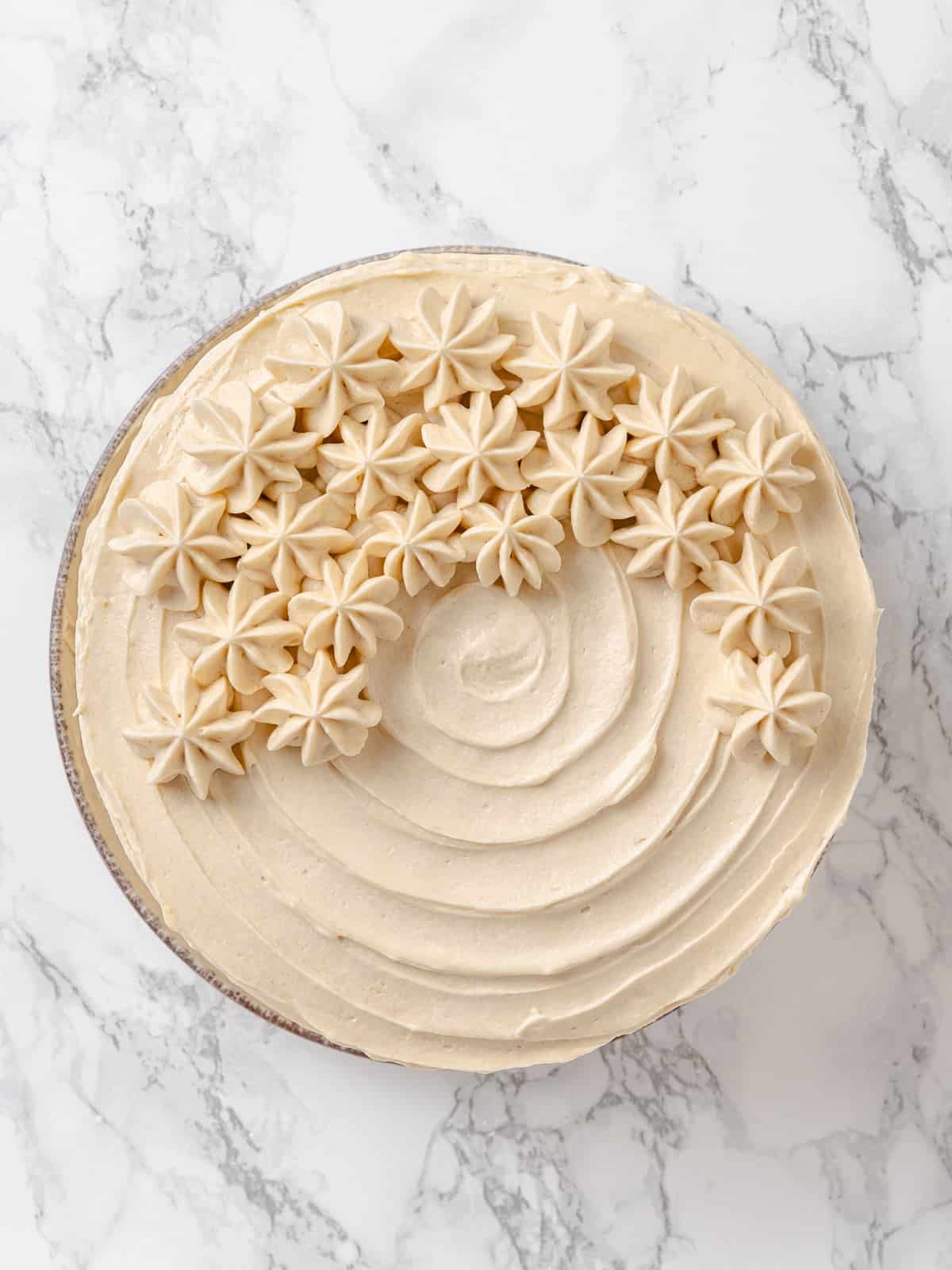 Maple frosting swirled thickly across a cake surface, showing creamy peaks and maple sweetness.
