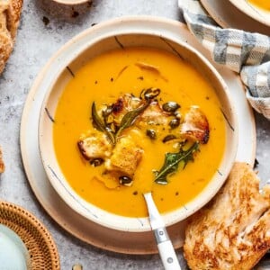 Bowl of deep orange squash soup highlighting rich roasted color.