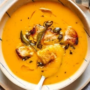 Velvety orange soup displayed in a clean white dish, perfect for cozy autumn dinners.