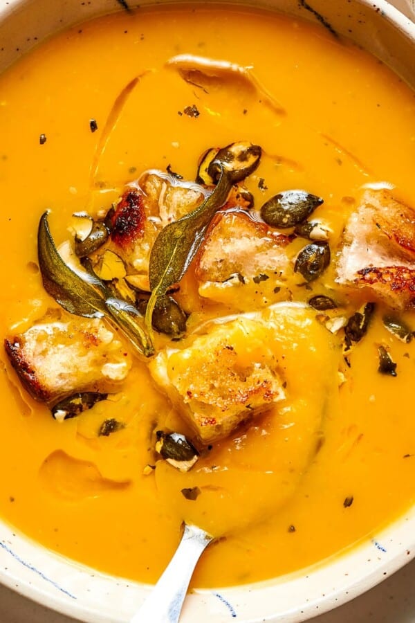 Velvety orange soup displayed in a clean white dish, perfect for cozy autumn dinners.