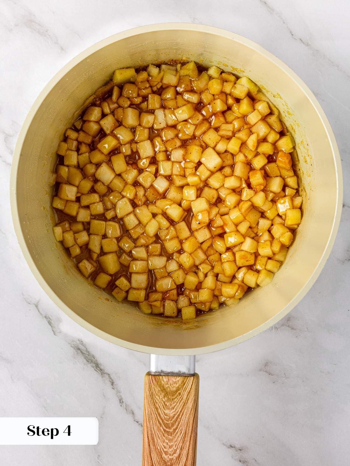 Diced apples bubbling in their own cinnamon-spiced sauce inside a saucepan.