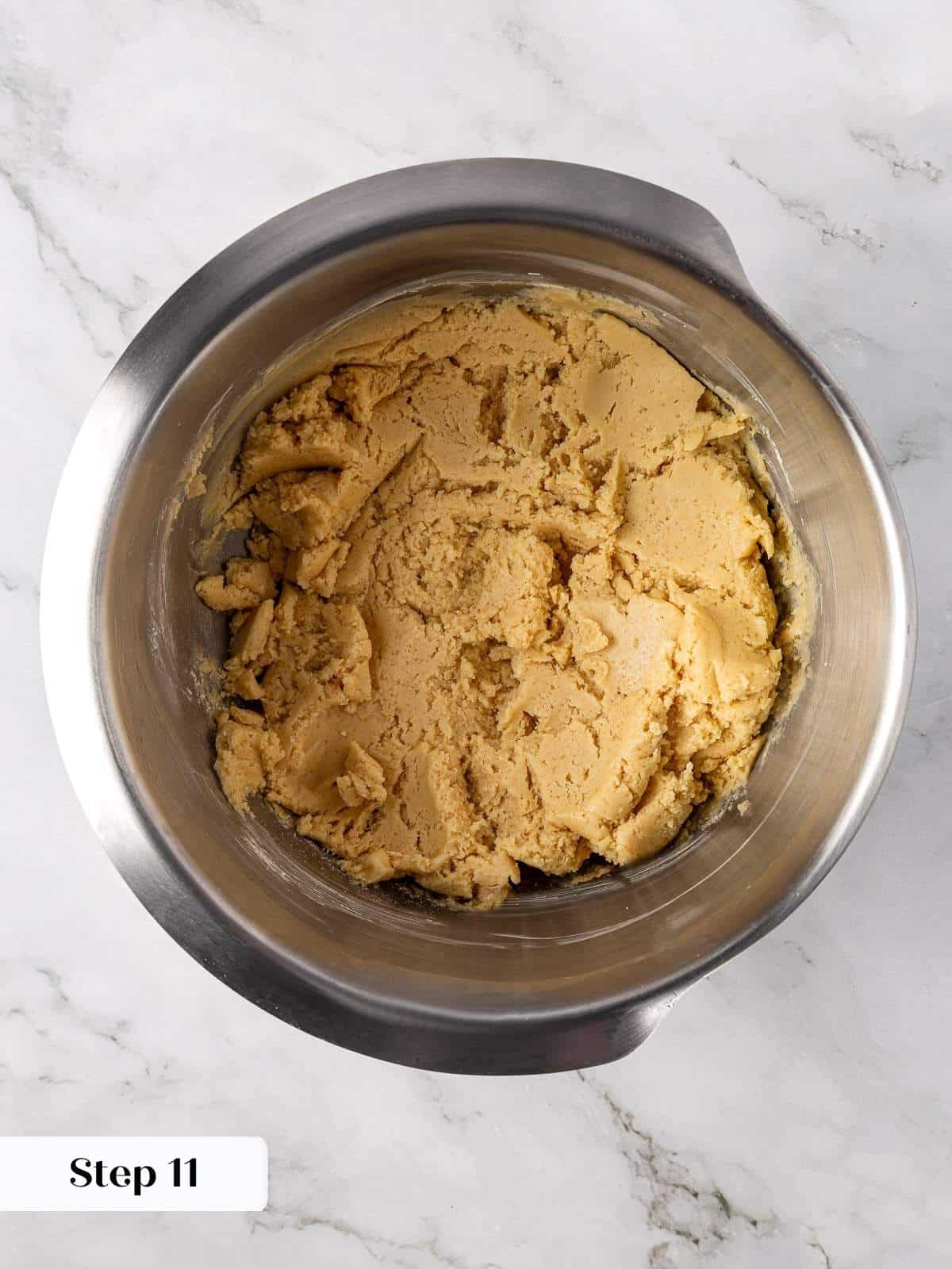 Finished apple cookie dough sitting thick and pale in a large mixing bowl.