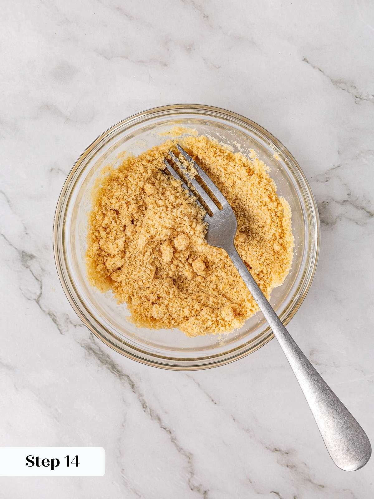 Brown sugar crumble mixture forming in a clear bowl after being stirred with melted butter.