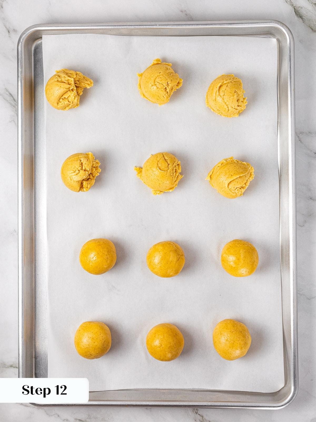 Rows of apple pie cookie dough balls resting on parchment paper before being pressed and filled.