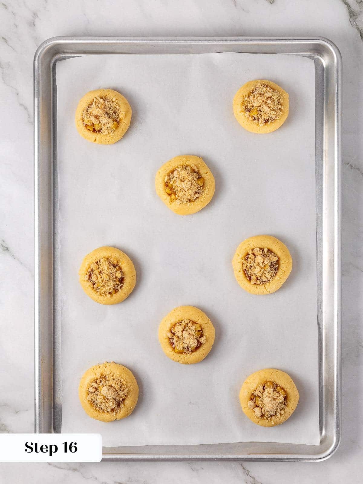 Unbaked apple pie cookies topped with brown sugar crumble before heading into the oven.