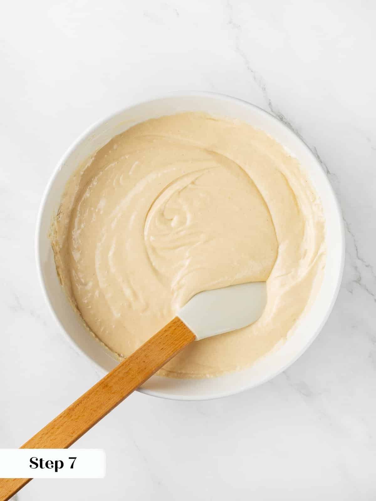 Mixing cranberry cake batter with a silicone spatula inside a large bowl.