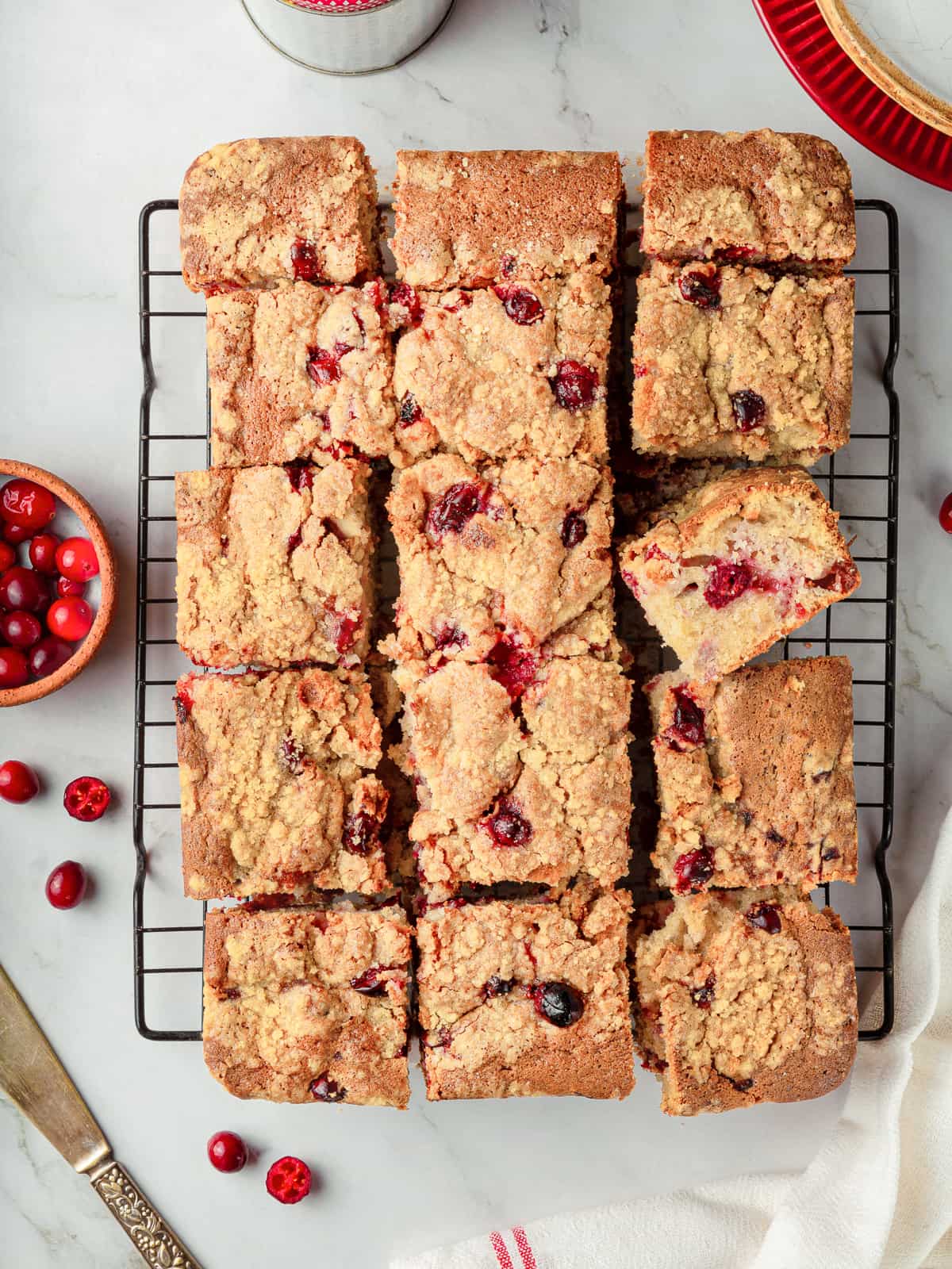 Cranberry cake sliced into neat squares revealing baked cranberries and streusel topping.