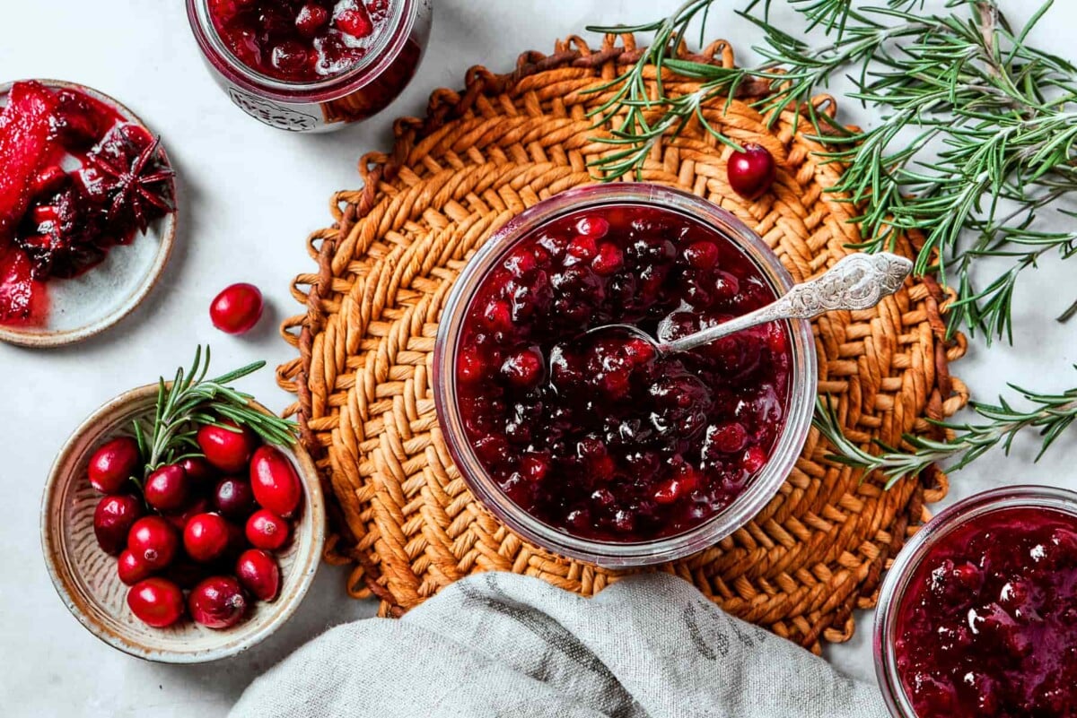 Bowl of cranberry sauce garnished with fresh rosemary sprigs for a festive holiday presentation.