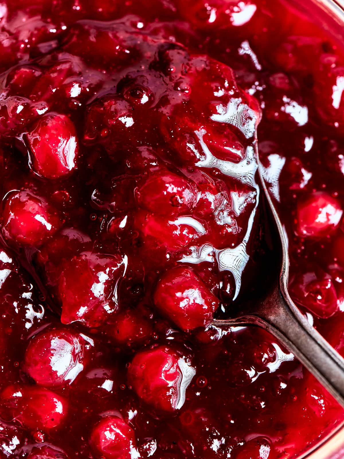 Close view of homemade cranberry sauce revealing its rich, jam-like consistency and deep red color.