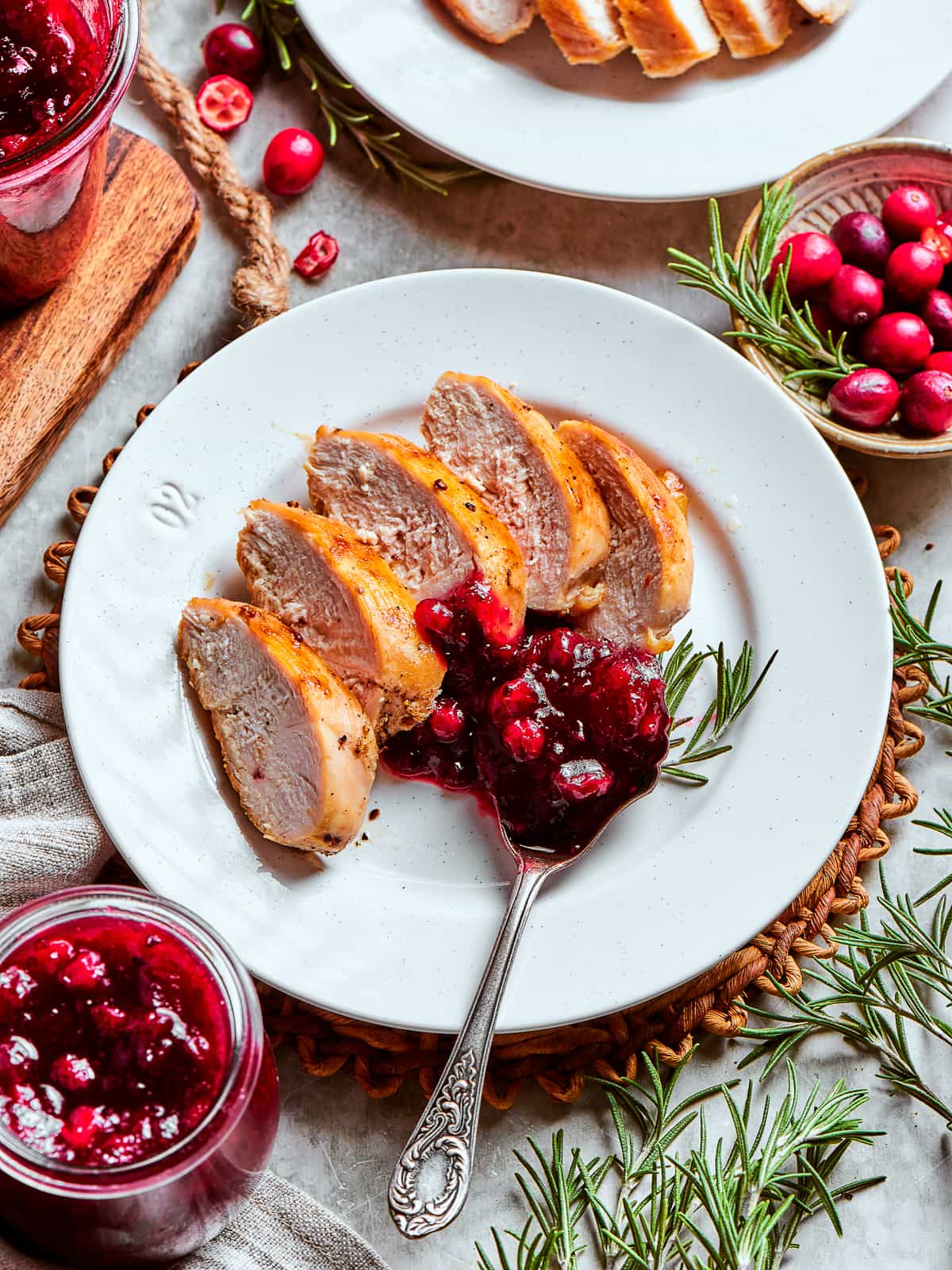 Cranberry sauce portioned on a white plate next to slices of turkey for Thanksgiving dinner.