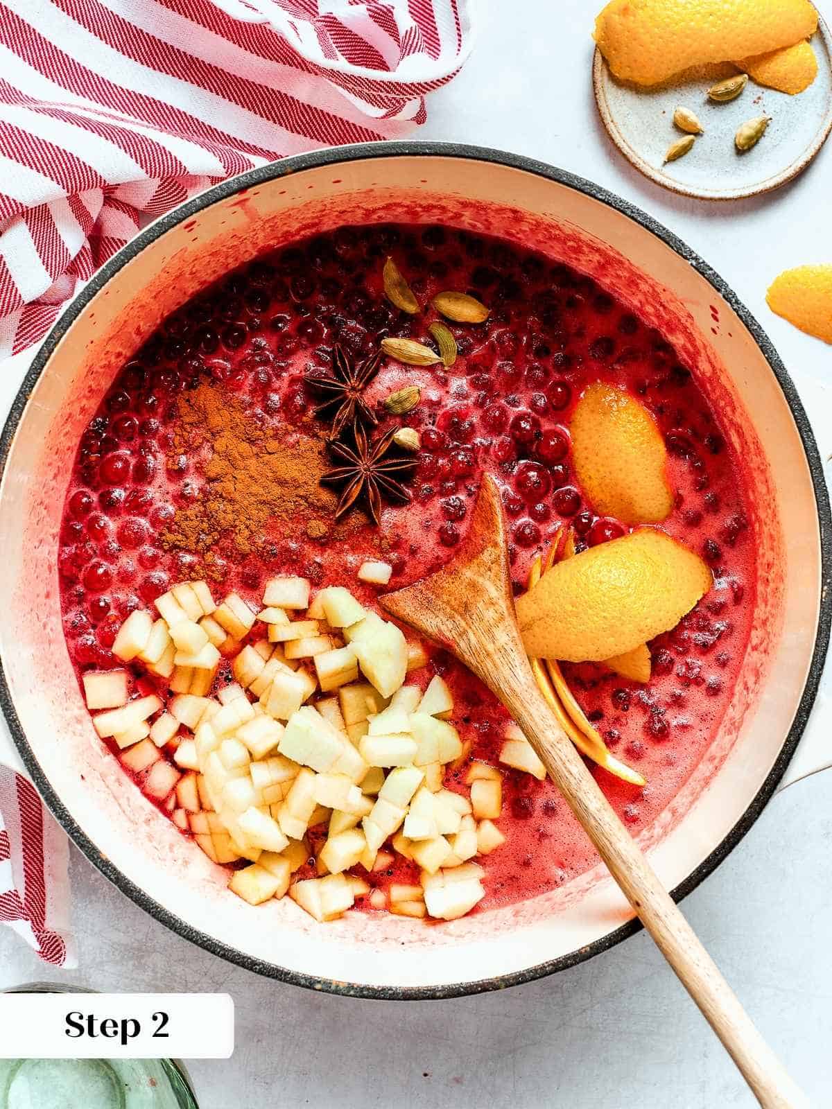 Saucepan of bubbling cranberries with warm spices infusing flavor during the cooking process.