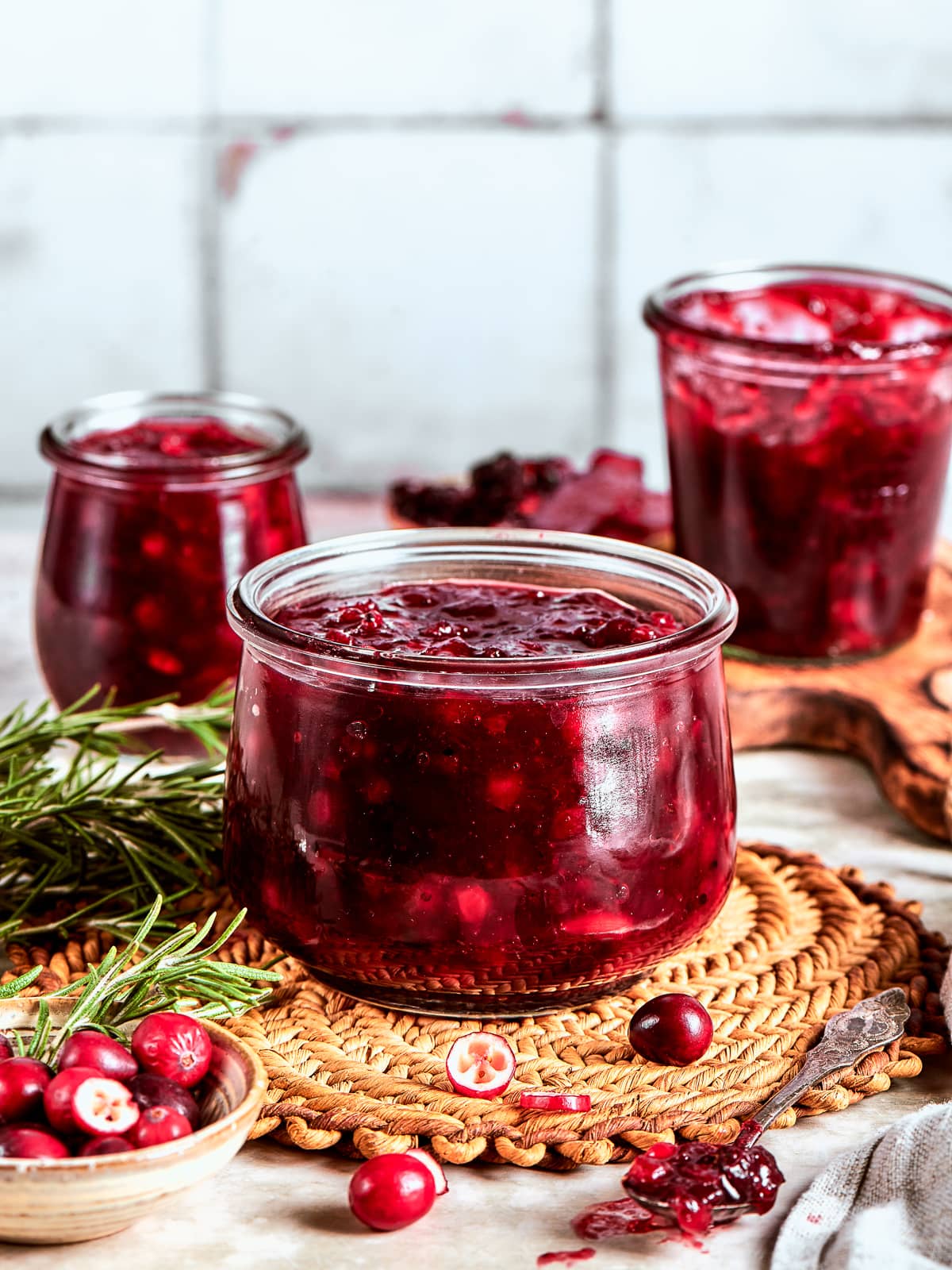 Three glass jars of cranberry sauce cooling on the counter ready to store in the fridge.