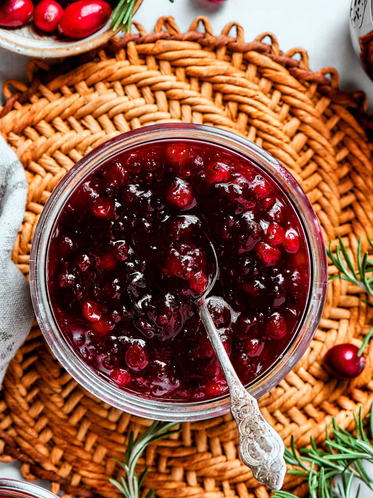 Bowl of bright red cranberry sauce on a woven placemat ready to serve for Thanksgiving dinner.